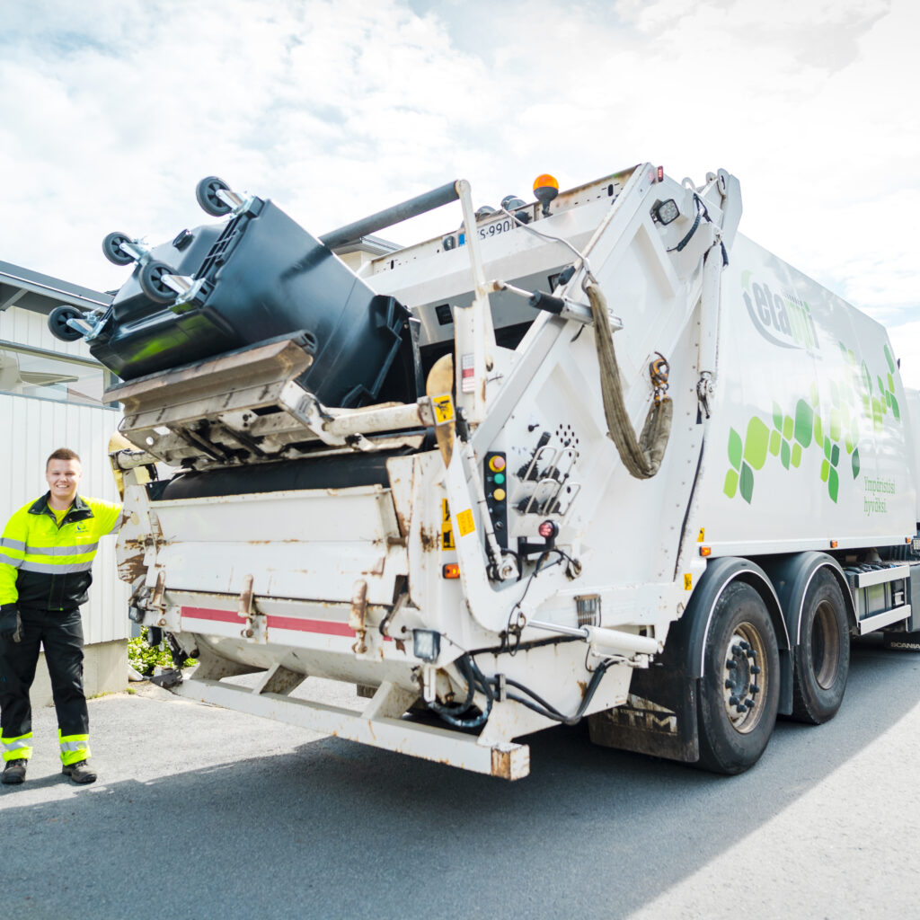 Jätteenkuljettaja tyhjää jäteastiaa jäteautoon.