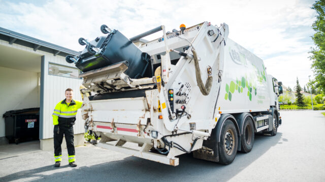 Jätteenkuljettaja tyhjää jäteastiaa jäteautoon.