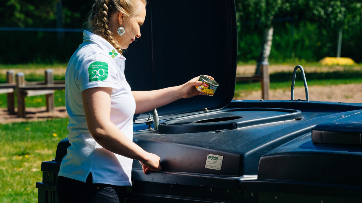 Nainen laittaa metallijätettä jäteastiaan.