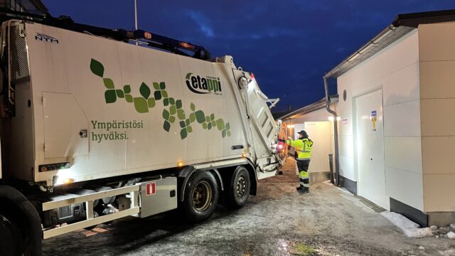 Jätekuljettaja tyhjentää jäteastiaa jäteautoon talvella.